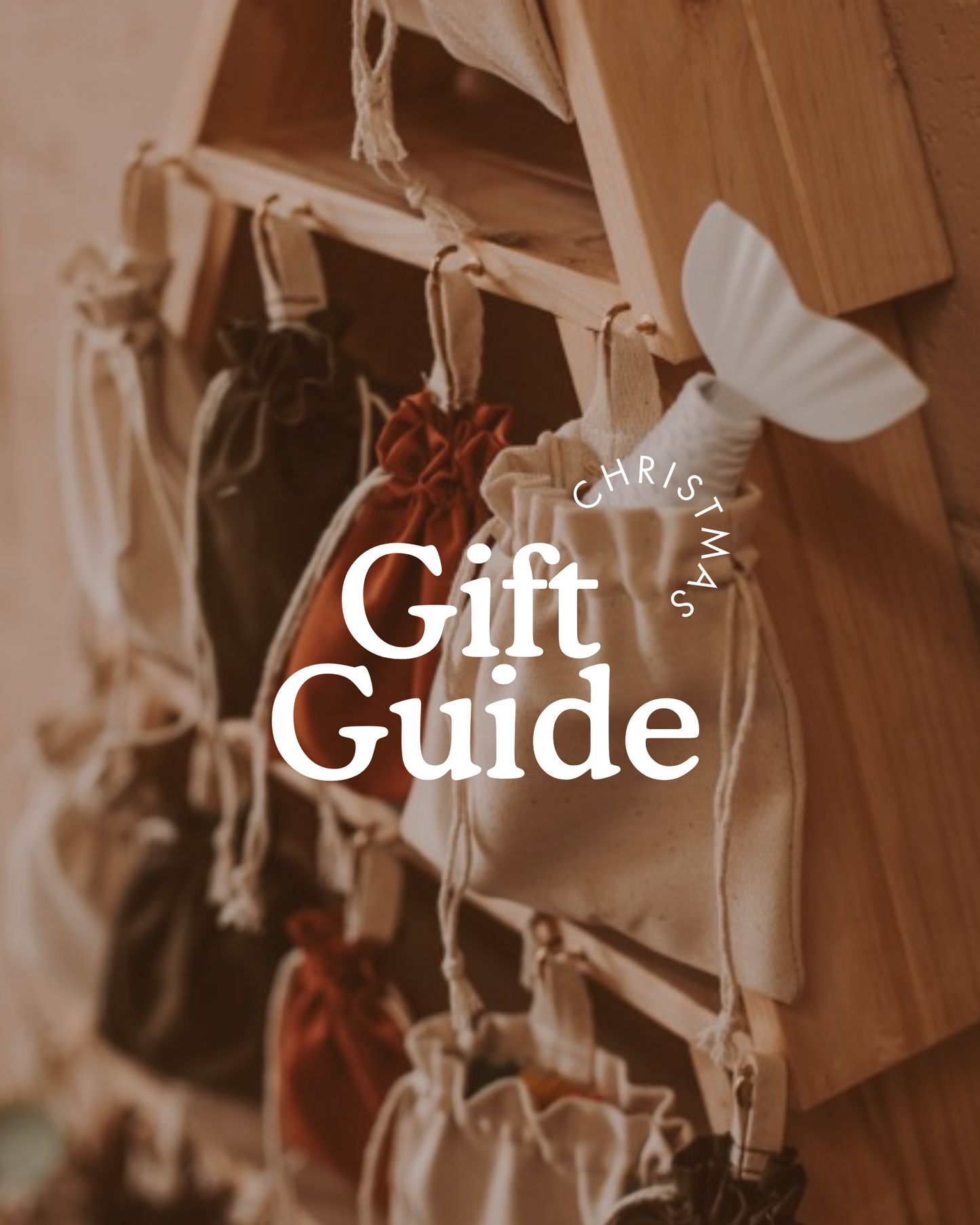Close-up of a wooden advent calendar filled with small drawstring fabric bags in warm Christmas colours, styled with a soft vintage feel. White text on the image reads ‘Christmas Gift Guide