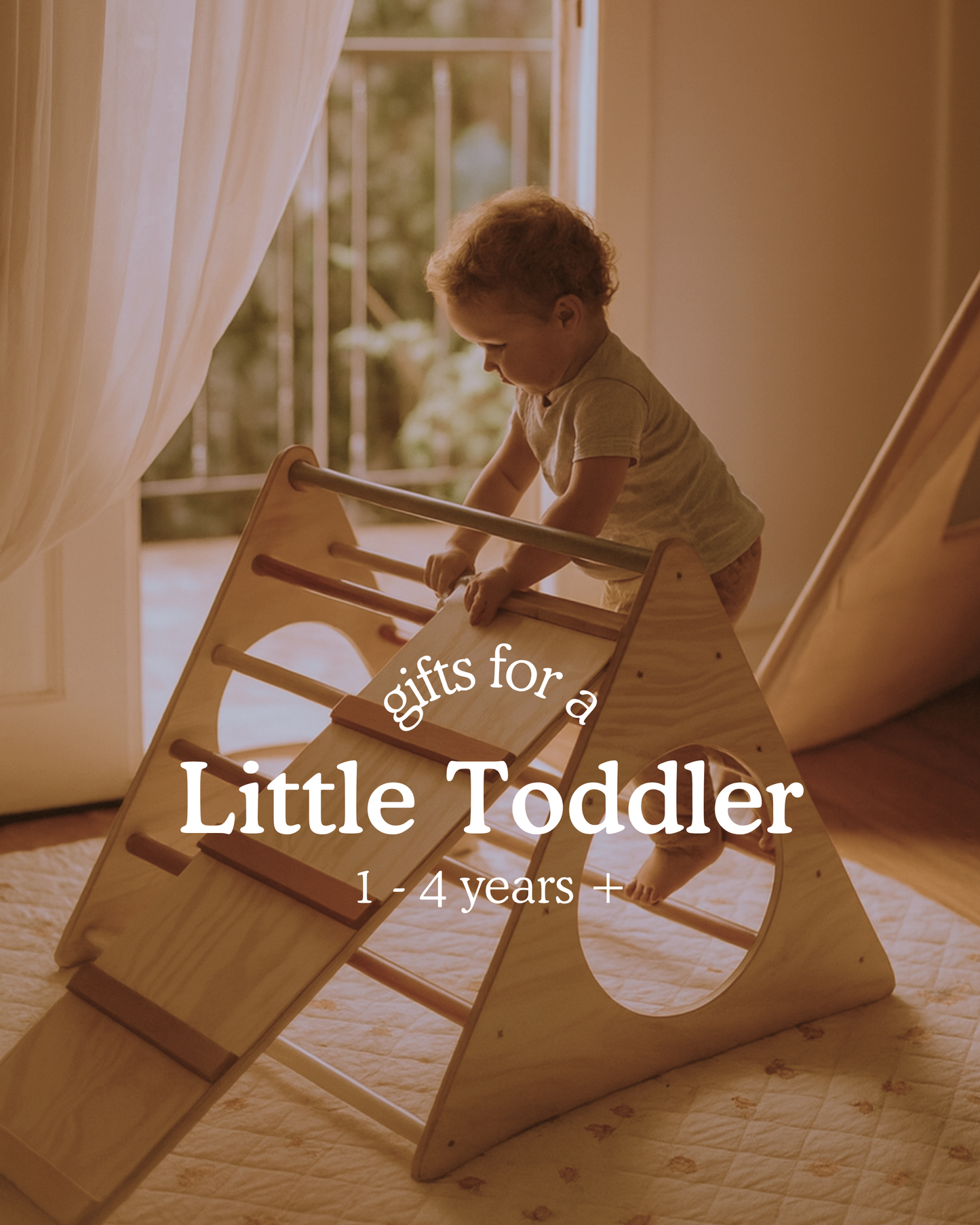 Toddler climbing a wooden Pikler triangle with a ramp inside a softly lit room. Text on image reads ‘Gifts for a Little Toddler, 1–4 years