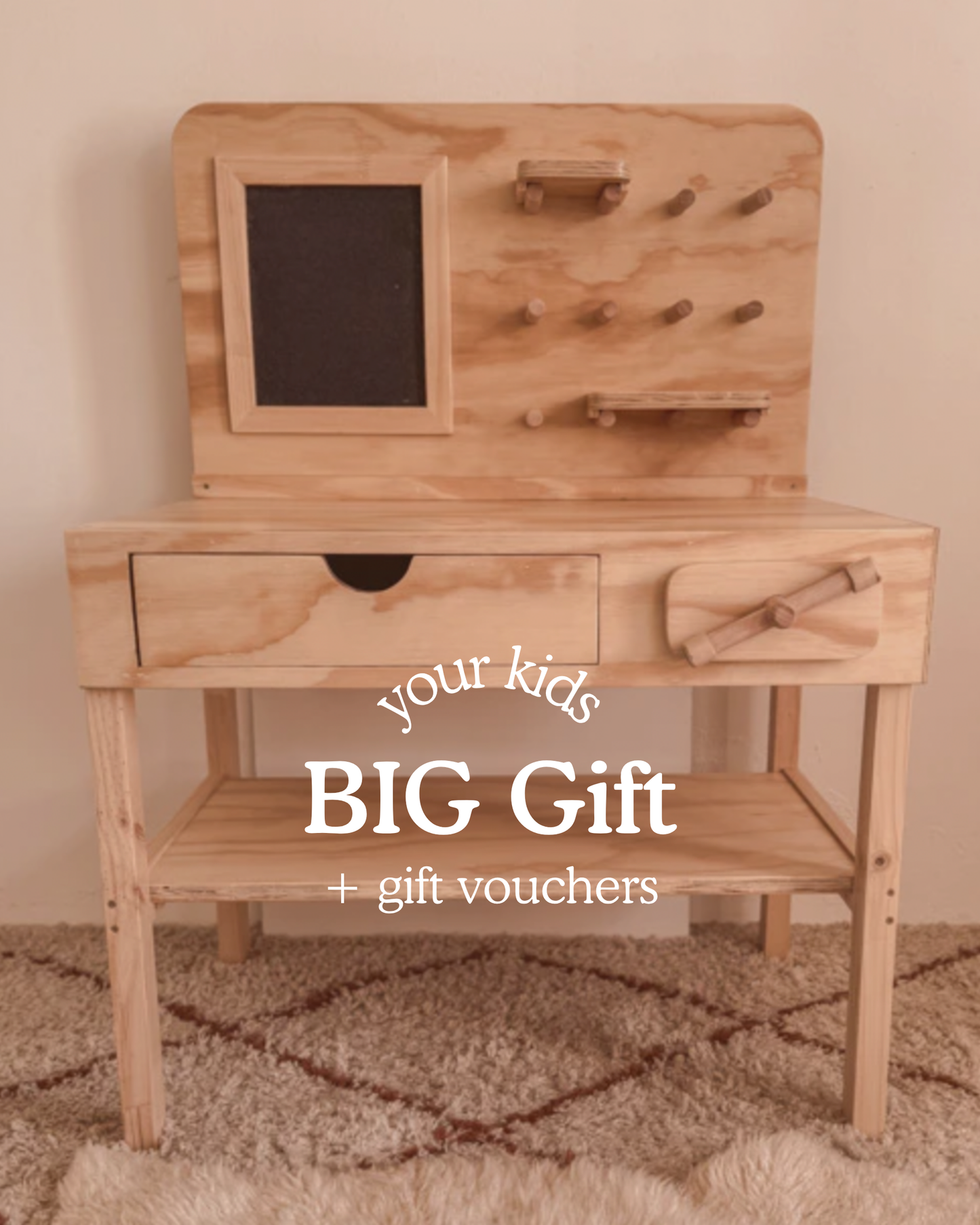 Wooden kids’ workbench with pegboard, drawer and shelves, photographed in a warm, cosy playroom. Text on image reads ‘Your Kids BIG Gift + gift vouchers.