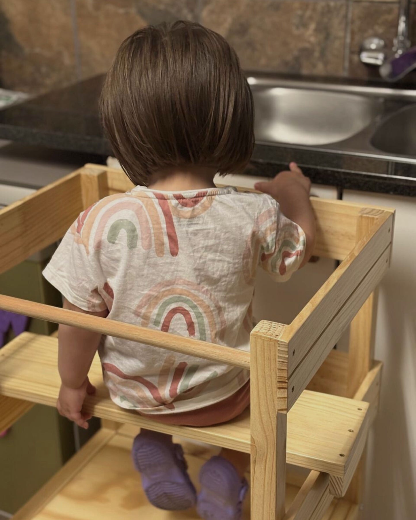 Rear view of toddler sitting in Learning Tower with seat add-on attachment