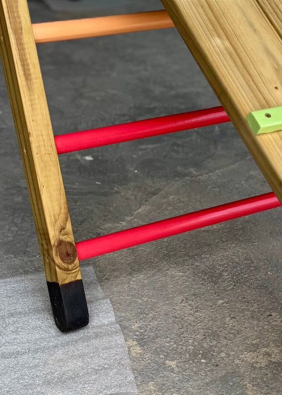 Close-up of the Outdoor Pikler Playground showing the bitumen booties on the timber feet and red climbing rungs, designed to protect the wood from ground moisture