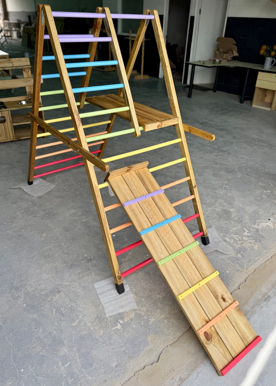 Full view of the Outdoor Pikler Playground with rainbow-coloured climbing rungs and a wooden slide, handcrafted from treated timber for outdoor use.