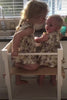 Two sibling toddlers sitting together in a Learning Tower with seat add-on, safe and sturdy design