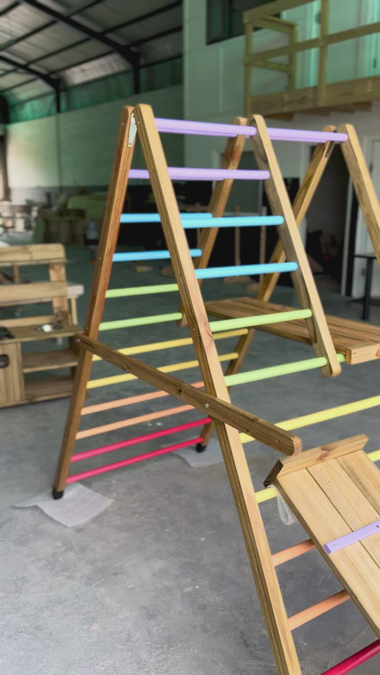 Load and play video in Gallery viewer, Video showing the Outdoor Pikler Playground fully expanded, featuring rainbow-coloured climbing rungs and a treated-timber frame, designed for outdoor use.
