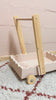 Scalloped wooden baby push walker in blush linen finish shown from side angle indoors.
